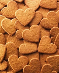 Close-up overhead view of a textured pile of golden-brown heart-shaped cookies filling the entire frame.