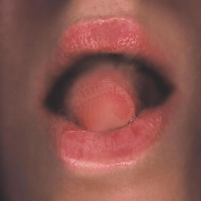 Close-up shot of a partially open mouth with glossy lips and a visible tongue inside, emphasizing the details of oral aesthetics.