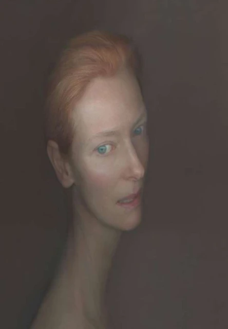 Headshot of an adult female with short red hair and light skin, set against a dark background in a portrait style.