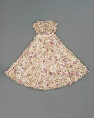 Strapless dress with floral embellishments in white, cream, and pink hues, photographed on a neutral grey background.