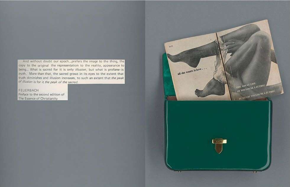 Still life of a glossy green purse with a book of legs sticking out. The scene is photographed on a grey surface.