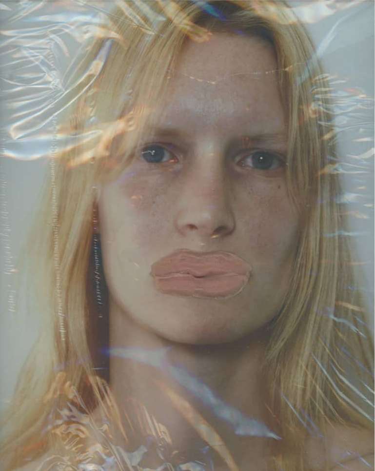 Close-up fashion shot of a blonde female model with a plastic wrap overlay, showcasing modern beauty and creative studio photography.