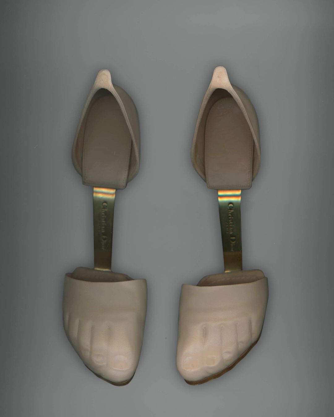 Pair of Christian Dior shoe stretchers on a grey background, presented in a studio product shot with bright, even lighting.