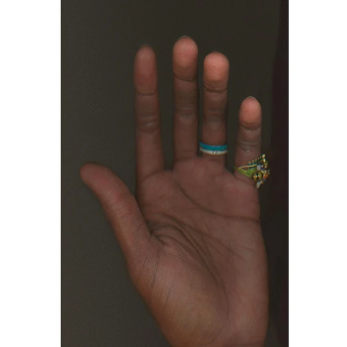 Close-up of an open human hand with rings on the fingers against a dark, shadowy background by Katerina Jebb.