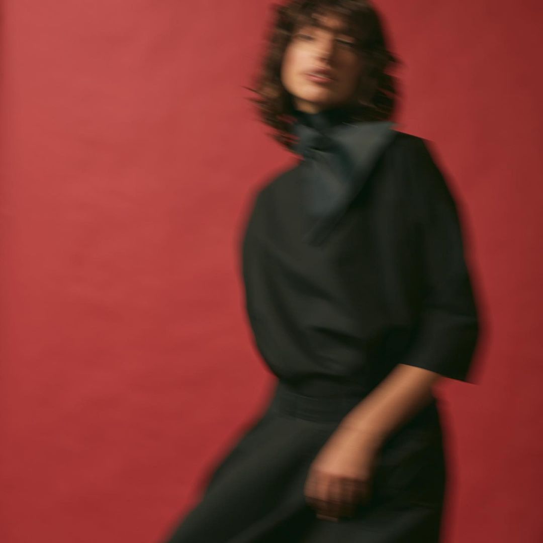 Motion-blurred portrait of a woman in a black top against a bold red background by photographer Kathrin Makowski.