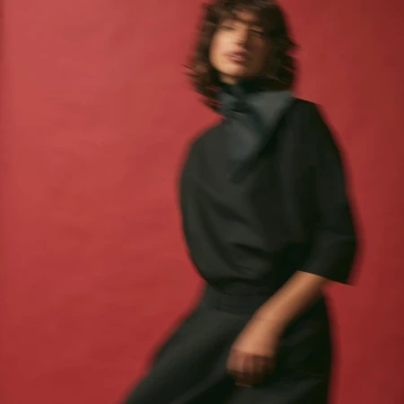Motion-blurred portrait of a woman in a black top against a bold red background by photographer Kathrin Makowski.