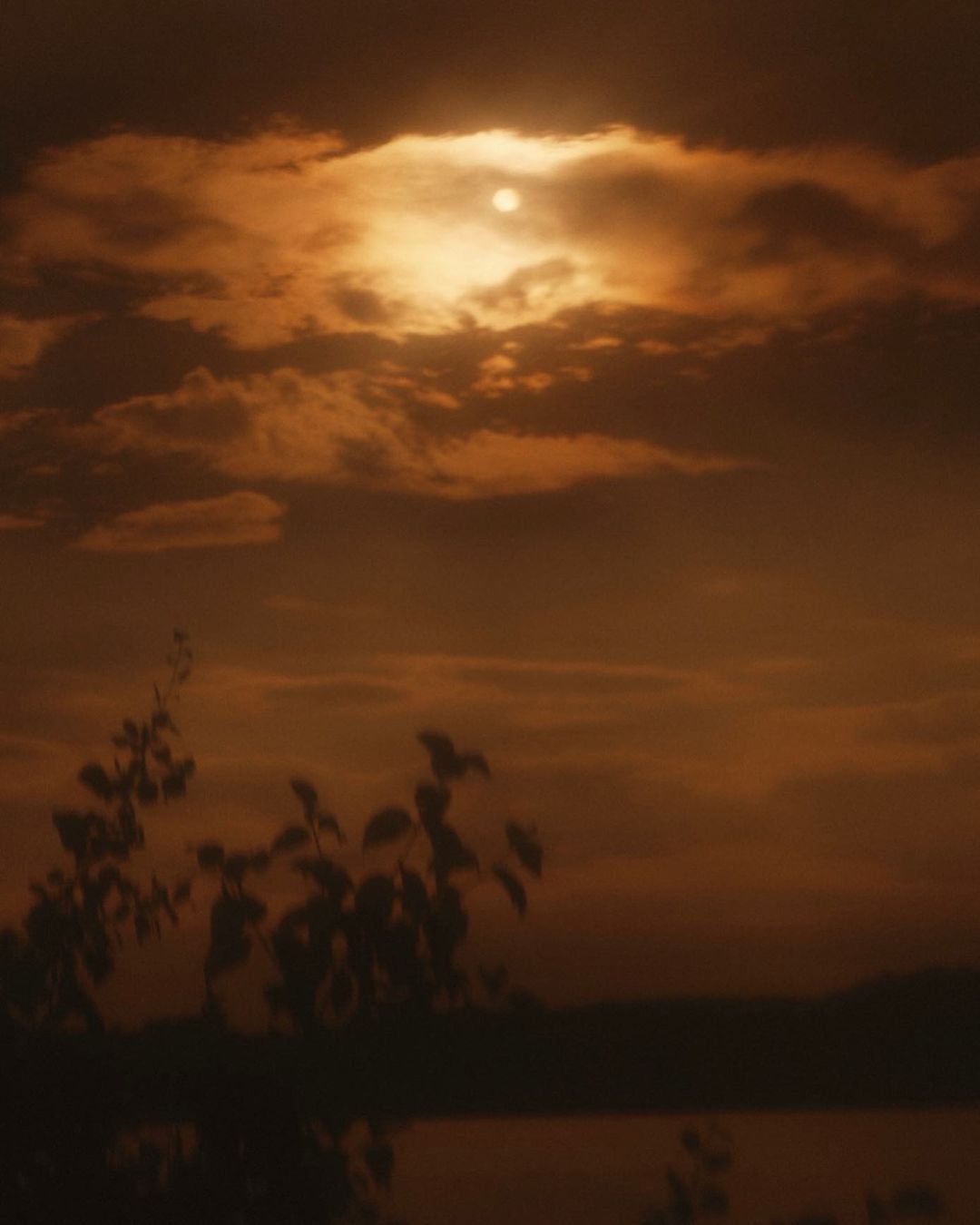 Dramatic sunset with clouds and the sun creating a vibrant, warm glow over the landscape, creating a serene and picturesque scene.