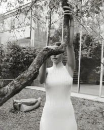 Model wearing a ribbed turtleneck sleeveless dress holding a tree trunk in Paris by photographer Kathrin Makowski