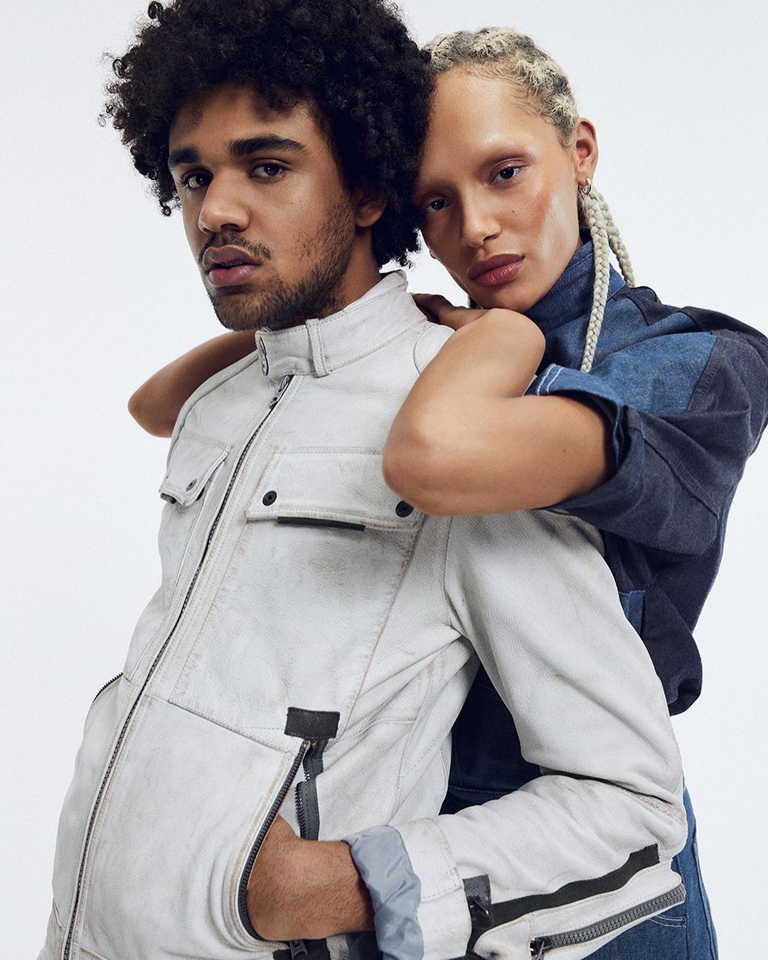 Portrait of a man in a white jacket with a woman in a blue denim top resting her chin on his shoulder