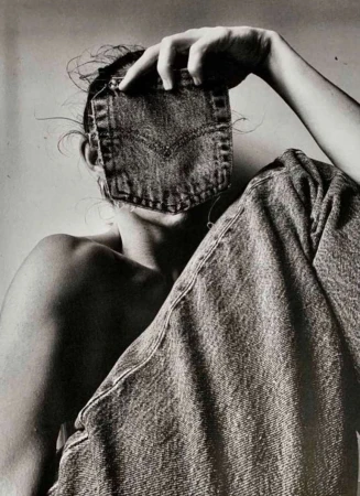 Monochrome portrait of a person obscured by a denim pocket, seated with jeans draped, creating an artistic fashion statement.