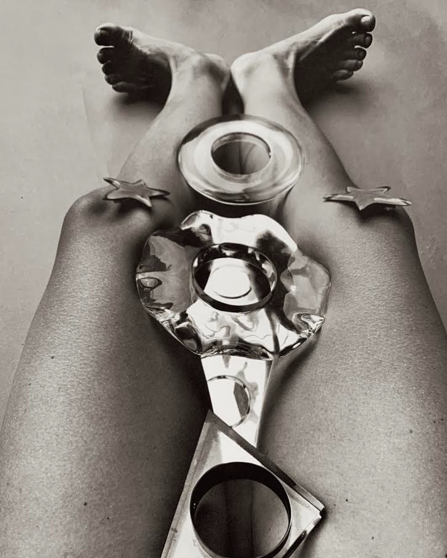 High angle black and white studio shot of legs and feet in the air, posing with transparent geometric shapes and gold star objects.
