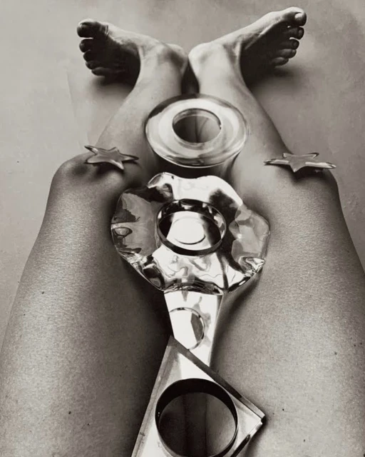 High angle black and white studio shot of legs and feet in the air, posing with transparent geometric shapes and gold star objects.