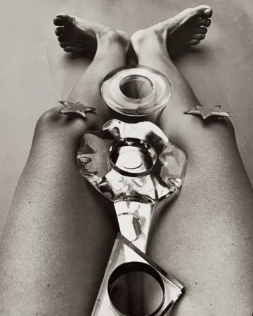 High angle black and white studio shot of legs and feet in the air, posing with transparent geometric shapes and gold star objects.