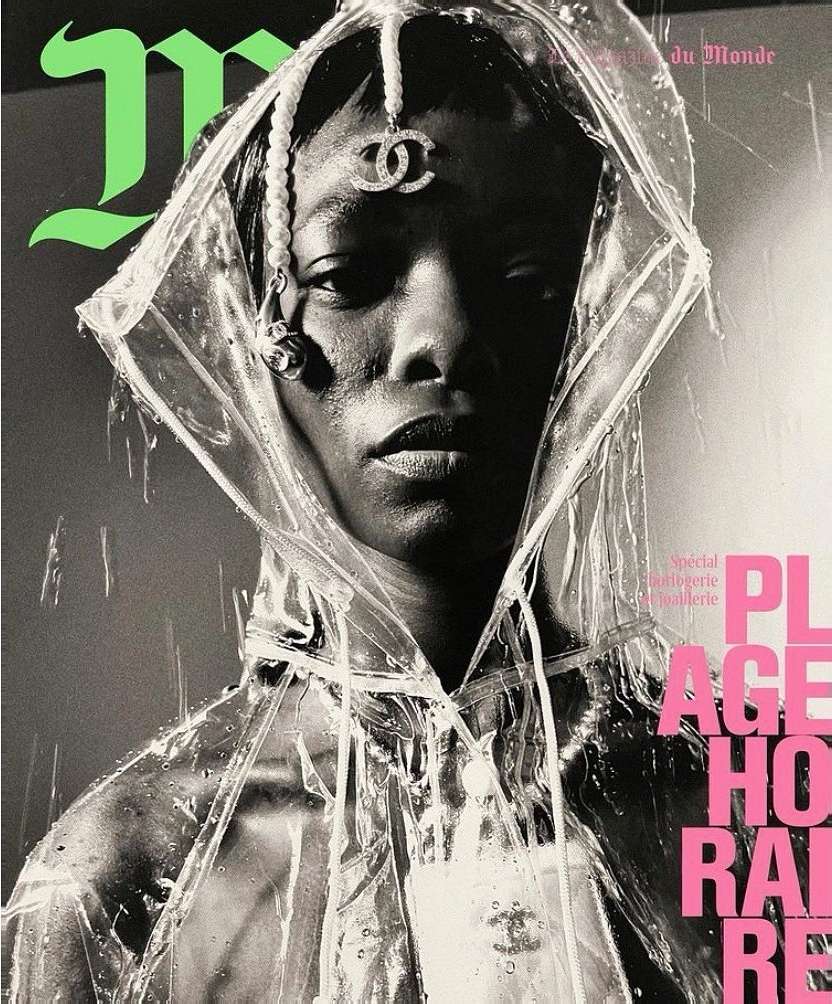 Magazine cover featuring a portrait of an adult female wearing a clear hooded raincoat and jewelry against a grey backdrop.