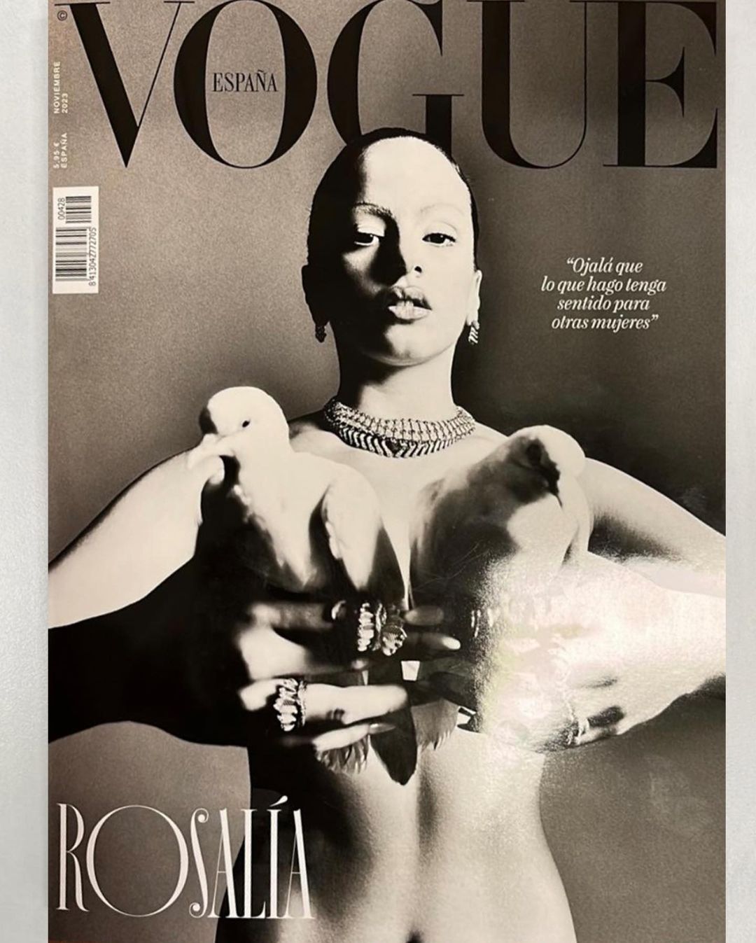Vogue España cover featuring Rosalía holding two white doves, adorned with jewelry, in a black-and-white photograph with magazine text.