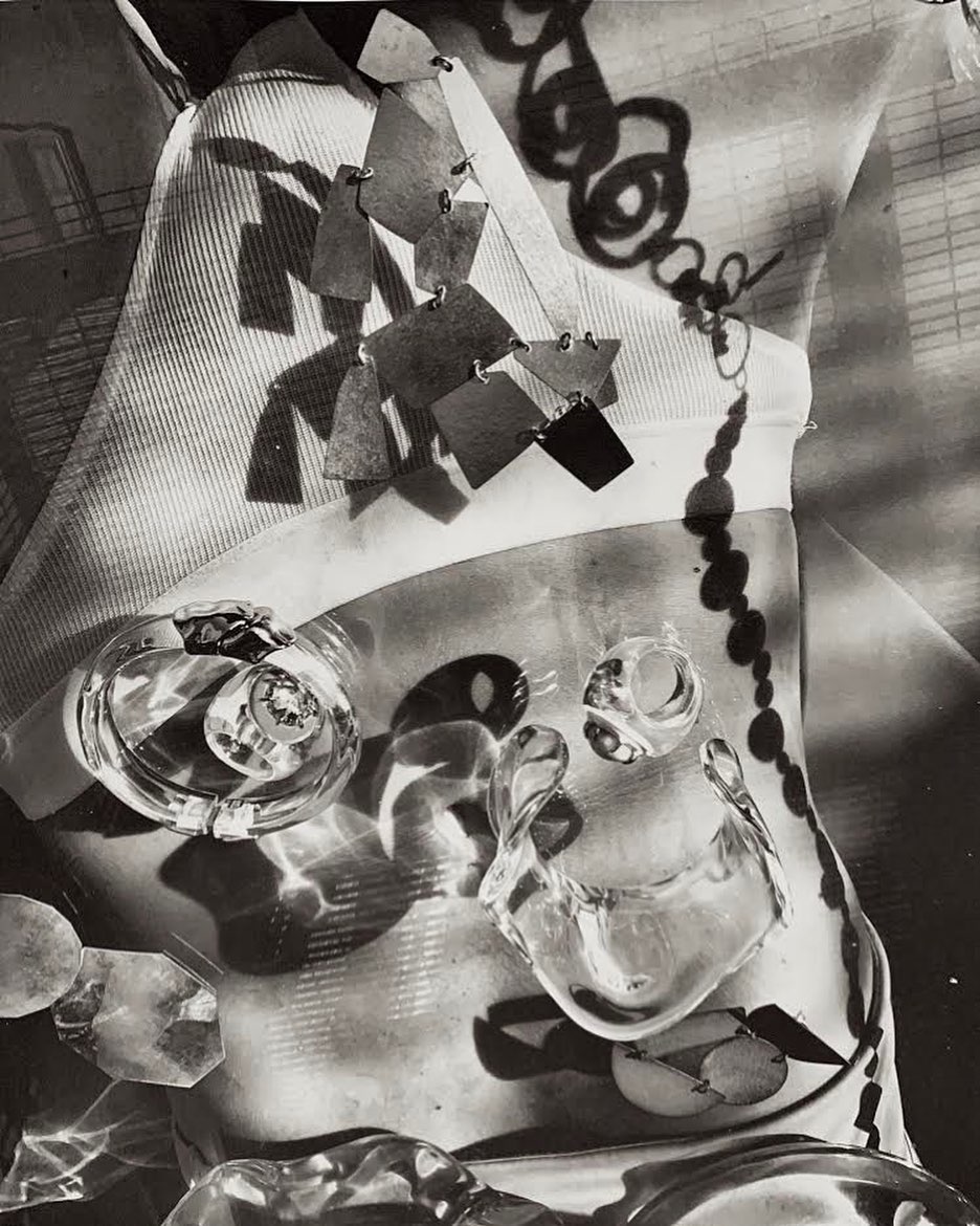 Abstract black and white studio shot of jewelry including clear plastic-like rings and a dangling necklace on fabric.