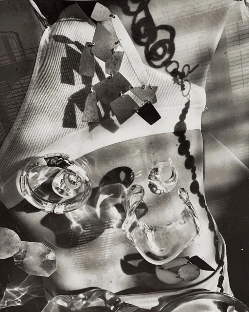 Abstract black and white studio shot of jewelry including clear plastic-like rings and a dangling necklace on fabric.