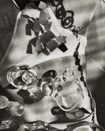 Abstract black and white studio shot of jewelry including clear plastic-like rings and a dangling necklace on fabric.