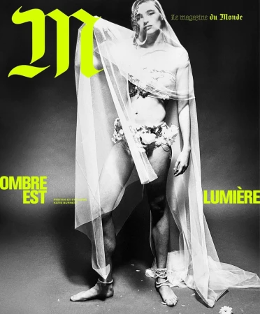 Magazine cover featuring a woman in floral decor and sheer fabric, against a dark background with bright lettering and high-contrast lighting.