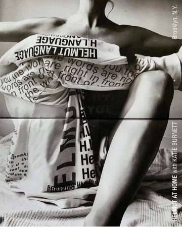 Monochrome portrait of a seated person wrapped in printed white fabric featuring bold typography