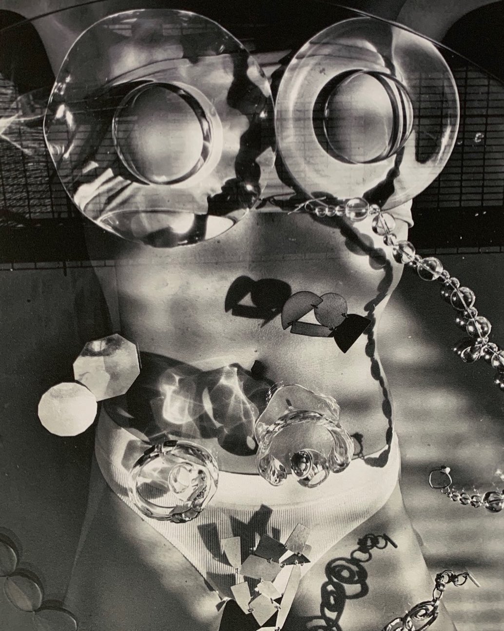 Monochrome torso with glass objects, jewelry, and geometric shapes creating an abstract, surreal, and artistic nude female figure.