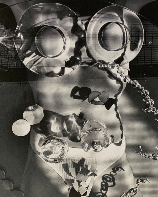 Monochrome torso with glass objects, jewelry, and geometric shapes creating an abstract, surreal, and artistic nude female figure.