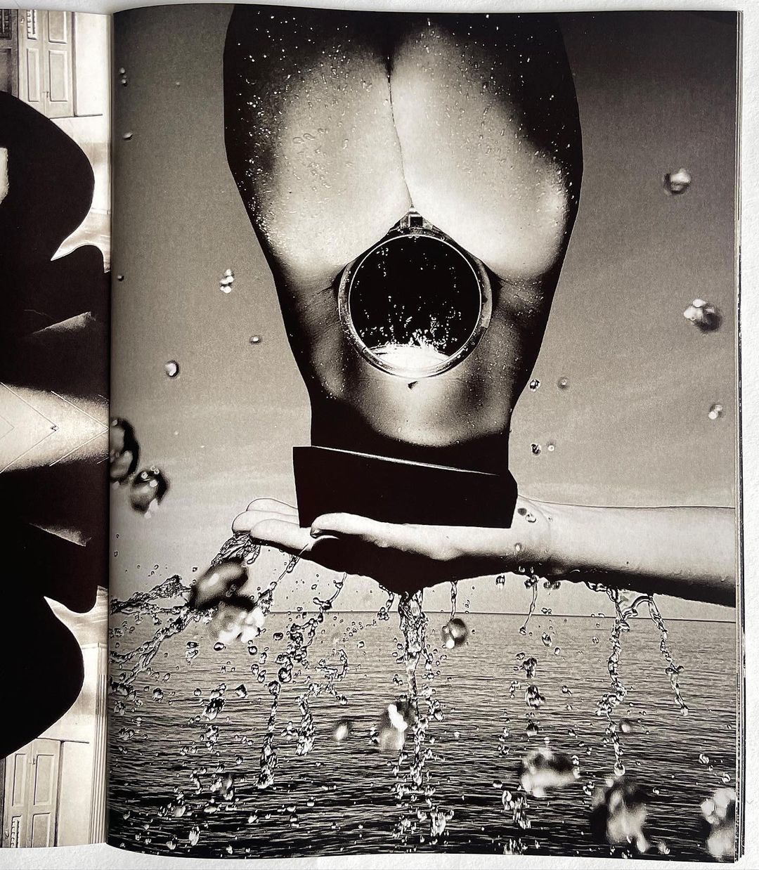 Monochrome nude female torso with circular mirror over ocean backdrop and water droplets in black and white artistic photography.