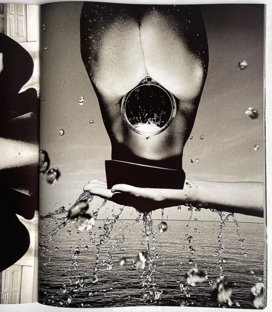 Monochrome nude female torso with circular mirror over ocean backdrop and water droplets in black and white artistic photography.