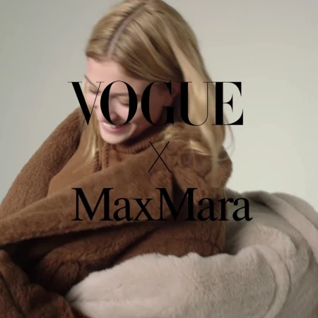 Blonde woman in a brown furry hooded sweatshirt in front of a beige backdrop, featuring overlaid black Vogue x Max Mara text.