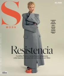 Magazine cover featuring Cynthia Nixon wearing a long grey coat with exaggerated padded shoulders and red sandals against a neutral backdrop.