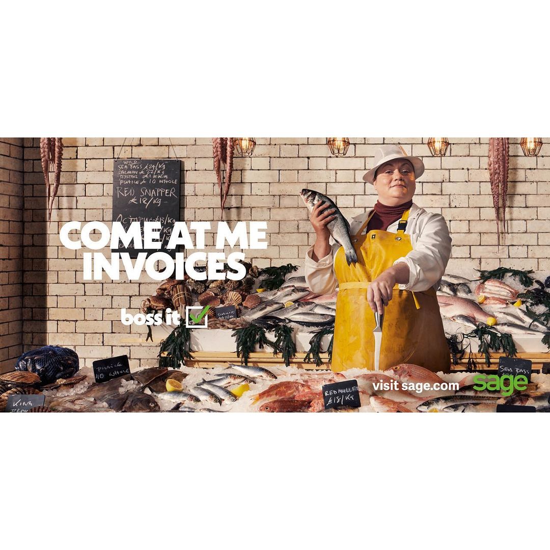 A fishmonger wearing a hat and apron holds a fish, standing behind a display of various seafood, with promotional text overlaid.