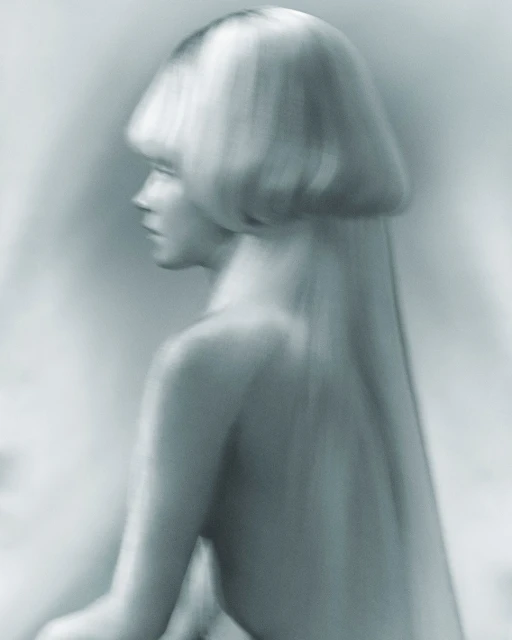 Monochromatic close-up of a woman with a blonde bob hairstyle in a profile pose with her back visible against a blurred background.