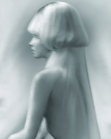 Monochromatic close-up of a woman with a blonde bob hairstyle in a profile pose with her back visible against a blurred background.
