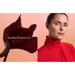 Woman in a vibrant red turtleneck blouse paired next to a dark flower with visible AnotherTomorrow text against a warm background.