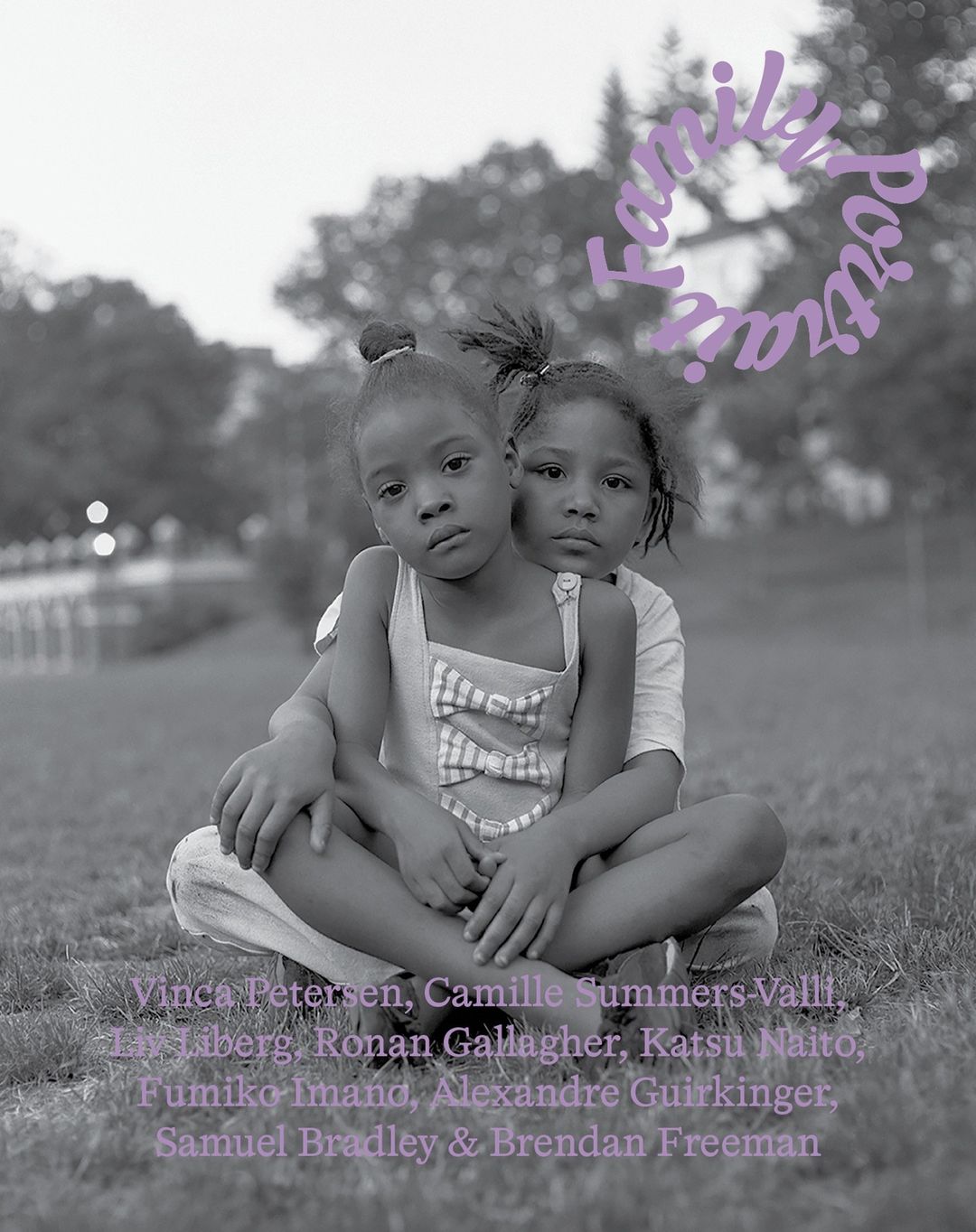 Black and white portrait of two young children sitting on grass with trees in the background. A text overlay is partially visible.