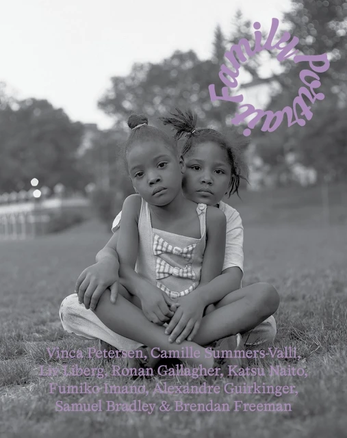 Black and white portrait of two young children sitting on grass with trees in the background.  A text overlay is partially visible.