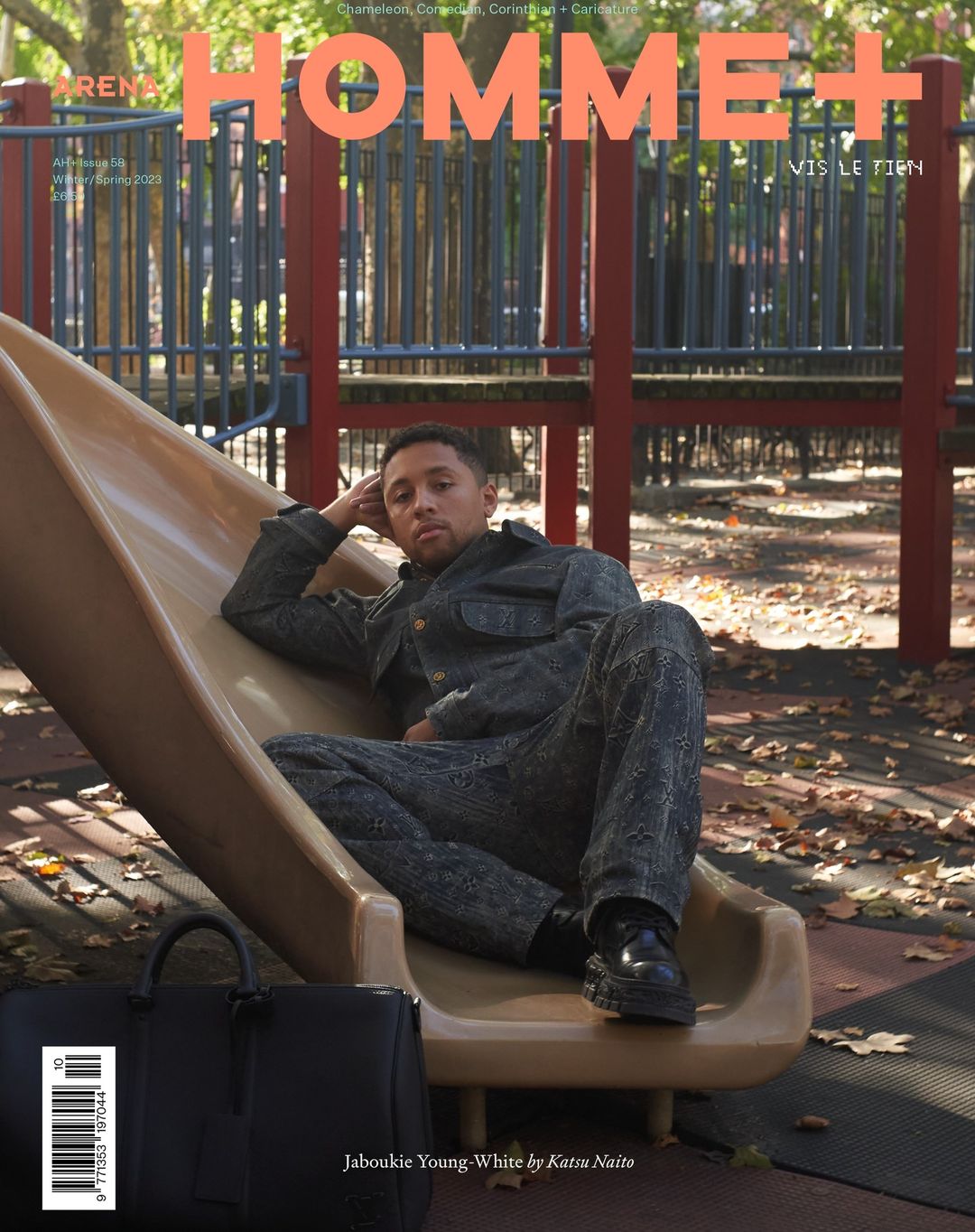 Magazine cover featuring an adult man lounging on a playground slide, with a black leather duffel bag visible in the foreground.