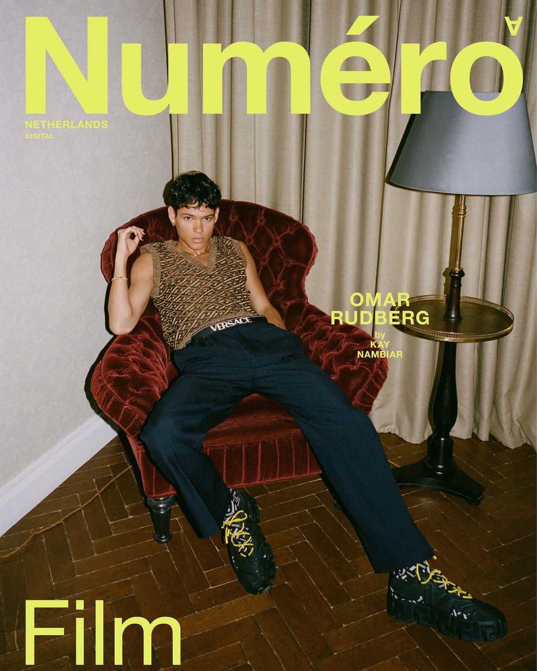 Magazine cover featuring Omar Rudberg in patterned vest and trousers, seated in a red chair beside a side table with a lamp.