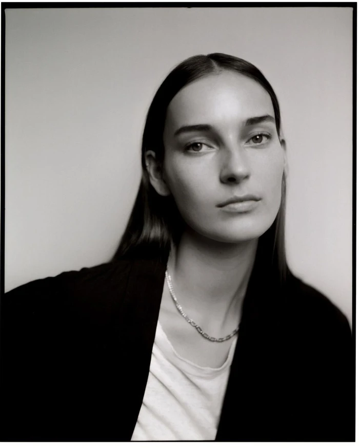 Portrait of a woman with dark hair wearing a white top and black blazer by photographer Kay Nambiar.