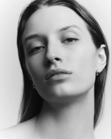 Close-up monochrome portrait of a woman with long hair and neutral expression against a plain white background.