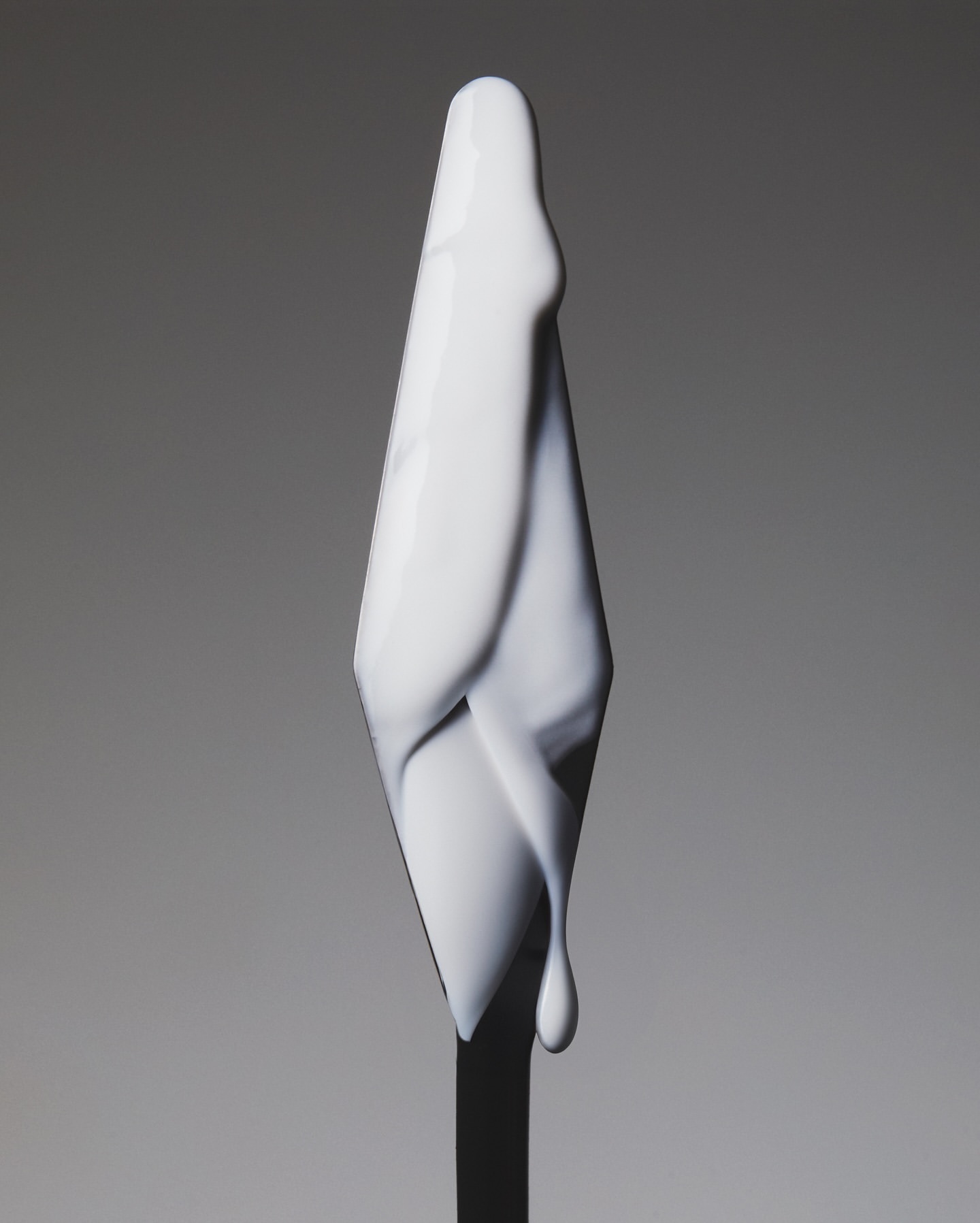 Abstract close-up of a white, stylized, cone-shaped object with smooth, flowing lines against a soft grey gradient background.