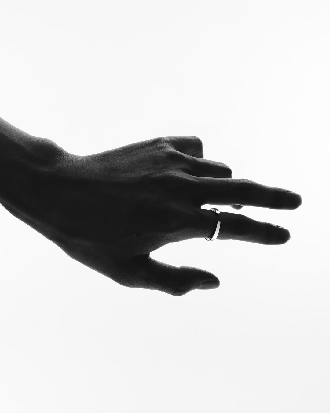 Close-up silhouette of a hand wearing a silver ring against a bright white background by Kazumi Miyamae