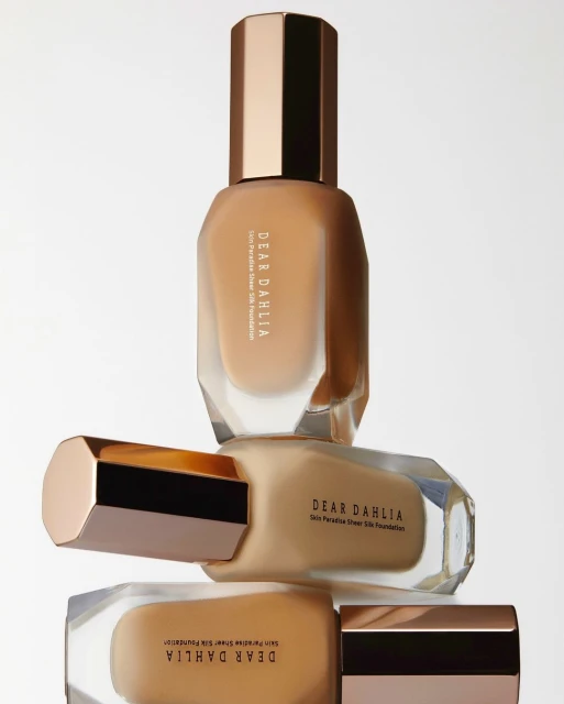Stack of Dear Dahlia Skin Paradise Sheer Silk Foundation bottles in various shades, presented against a clean, bright background.