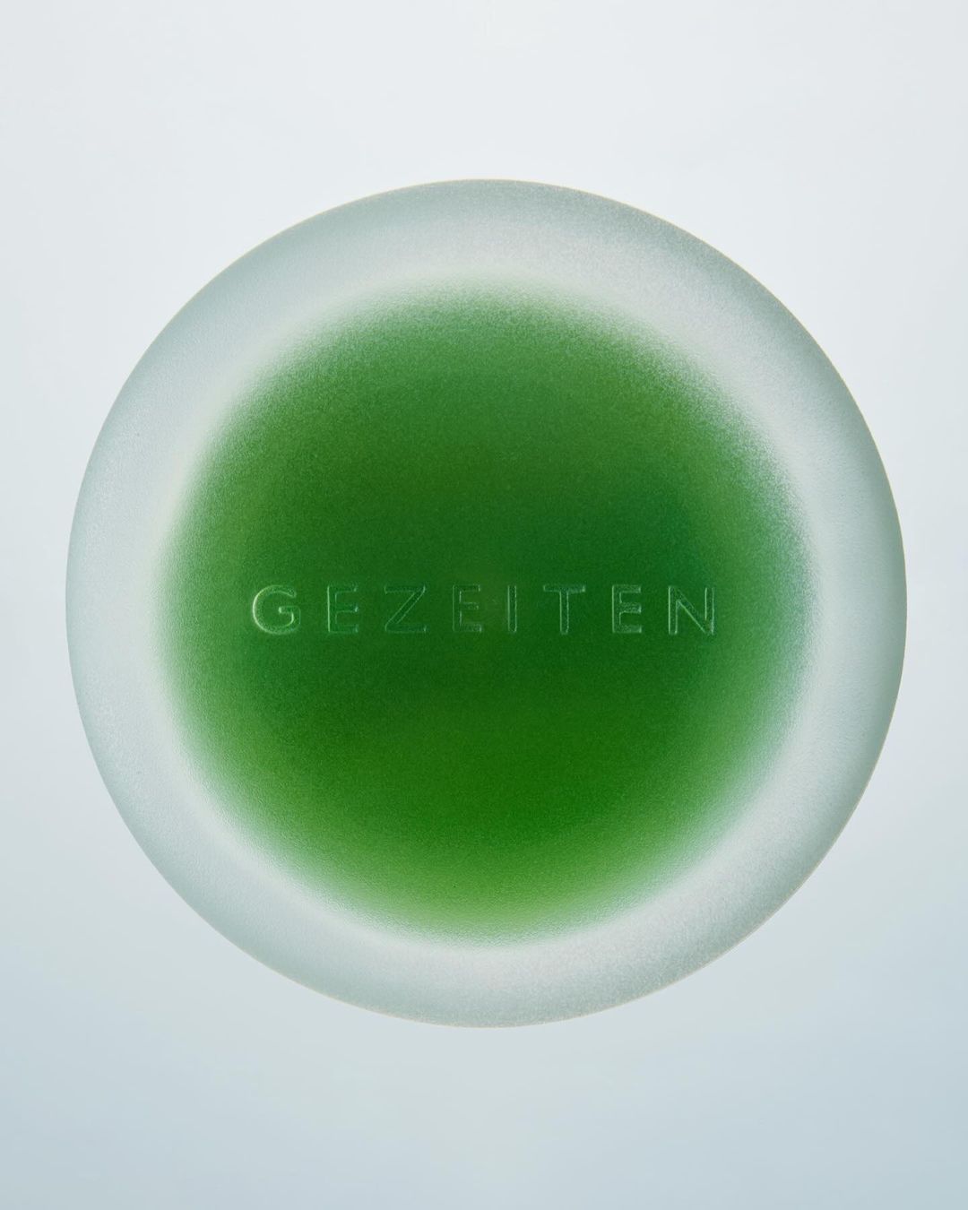 Green and white abstract orb with raised 'GEZEITEN' text in center against a pale background, showing texture and depth.
