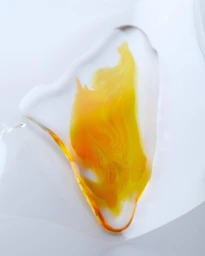 Close-up abstract shot of vibrant yellow and orange liquid resin pooled on a white surface by Kazumi Miyamae