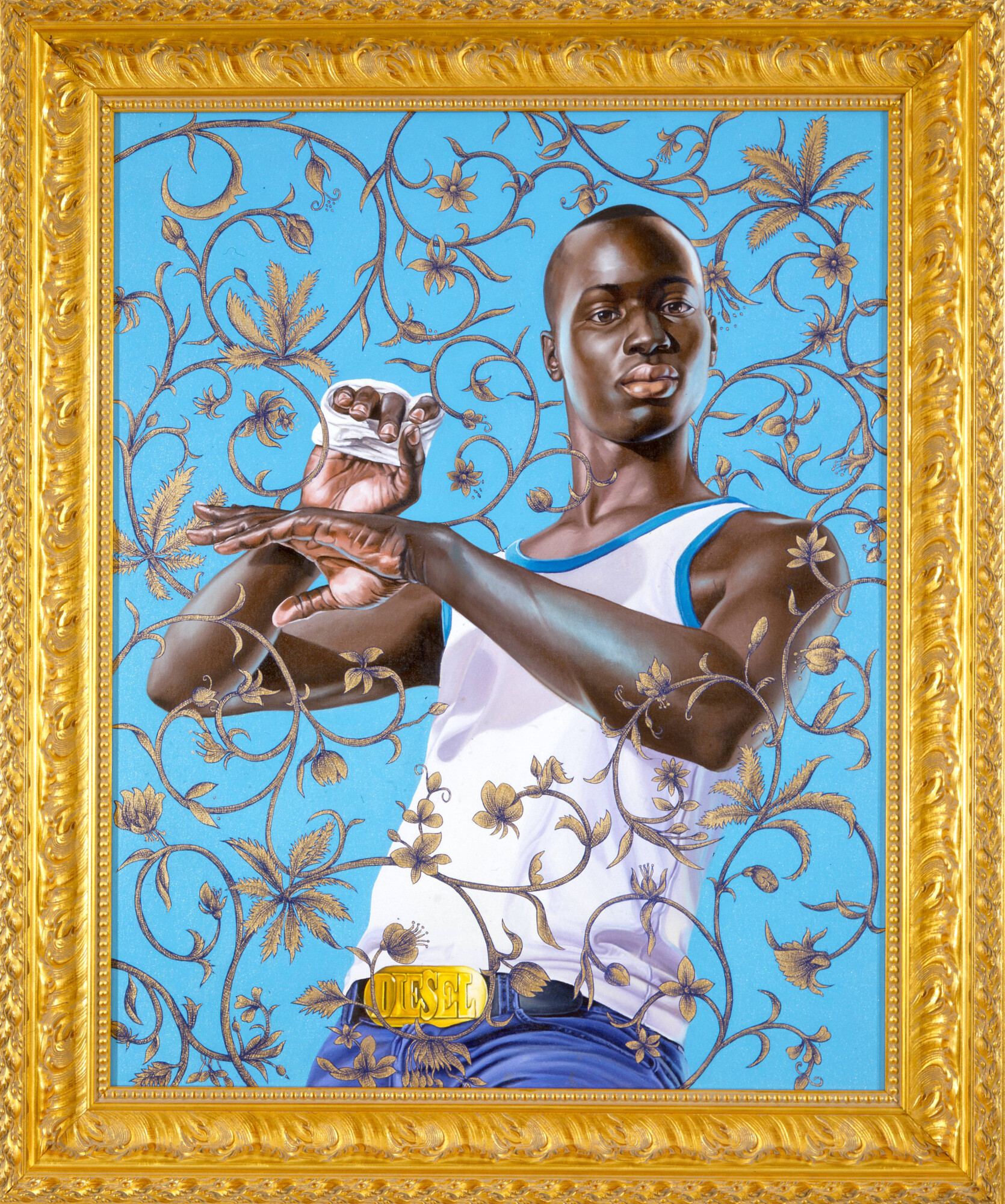 Portrait of a Black man in a white tank top and jeans with a Diesel belt, set against a blue floral background in a gold frame.