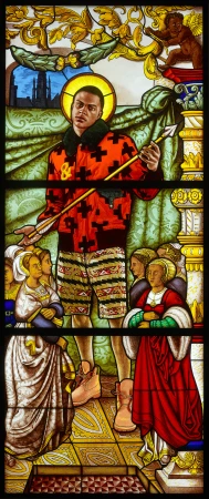 Stained glass artwork featuring a figure in contemporary clothing amidst historical elements and characters, blending modern and classic styles.