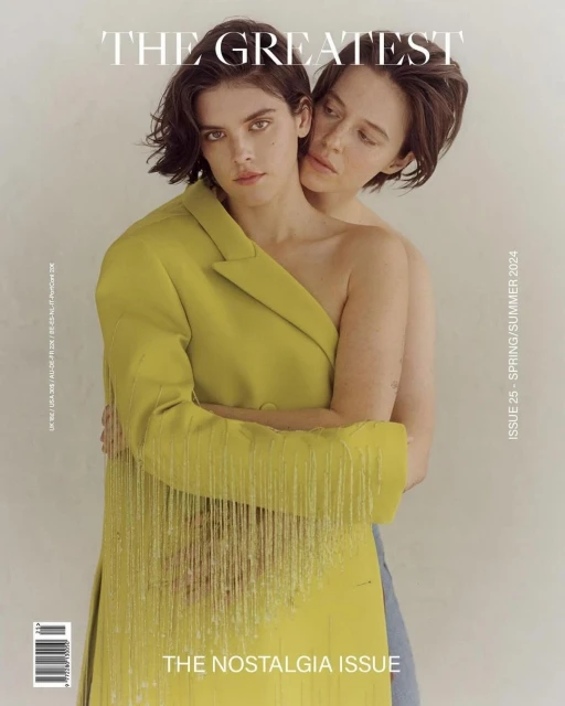 Magazine cover featuring two adult women embracing, one wearing a yellow fringed blazer, against a light background.