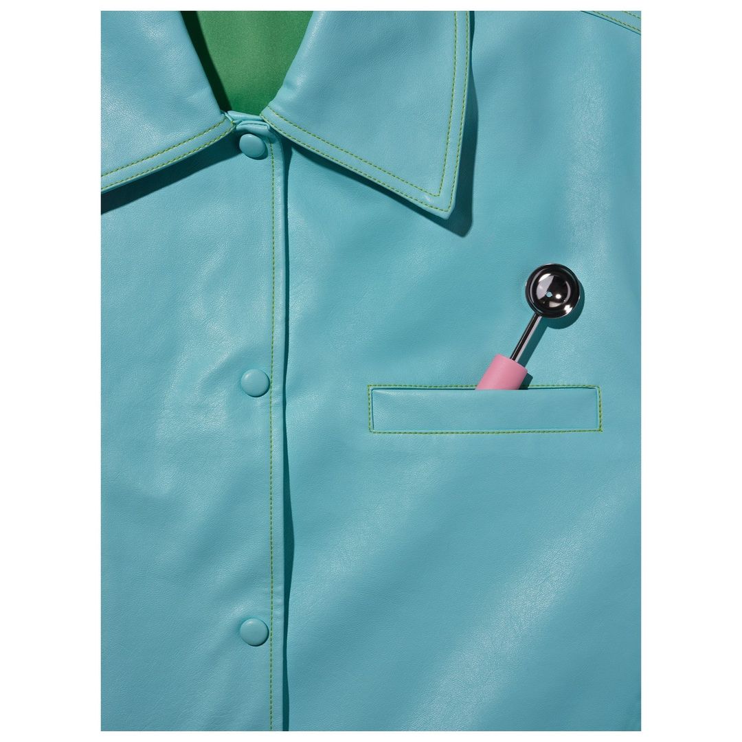Close-up shot of a light blue collared shirt featuring a pocket square and a metal object inside the pocket.