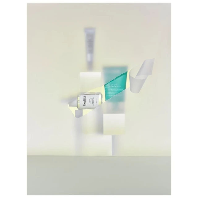Product photography featuring skincare tubes on stacked white blocks, surrounded by folded white paper, creating a modern and minimalist beauty concept.